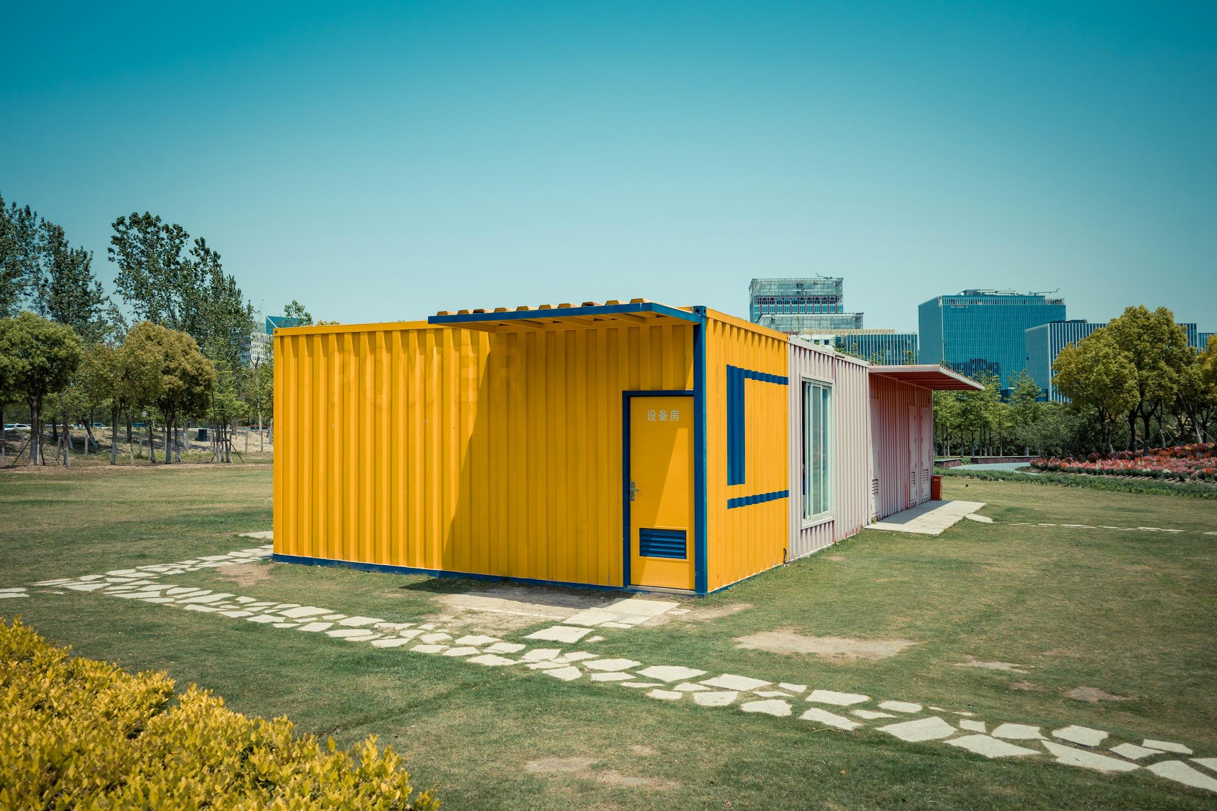 Compact converted container cabin with a door and window standing on a lawn