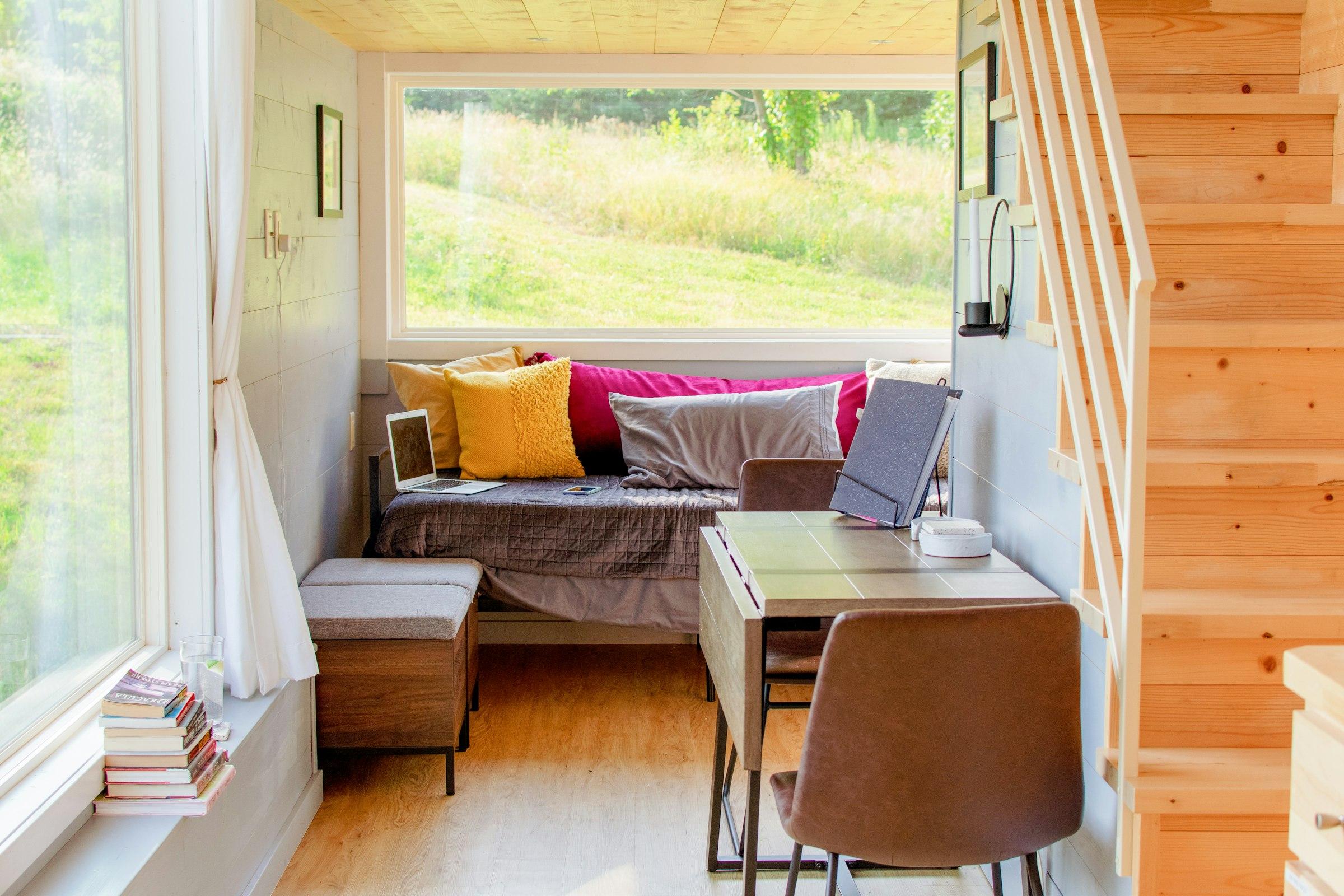 A sunlit desk and window seat inside a compact cabin